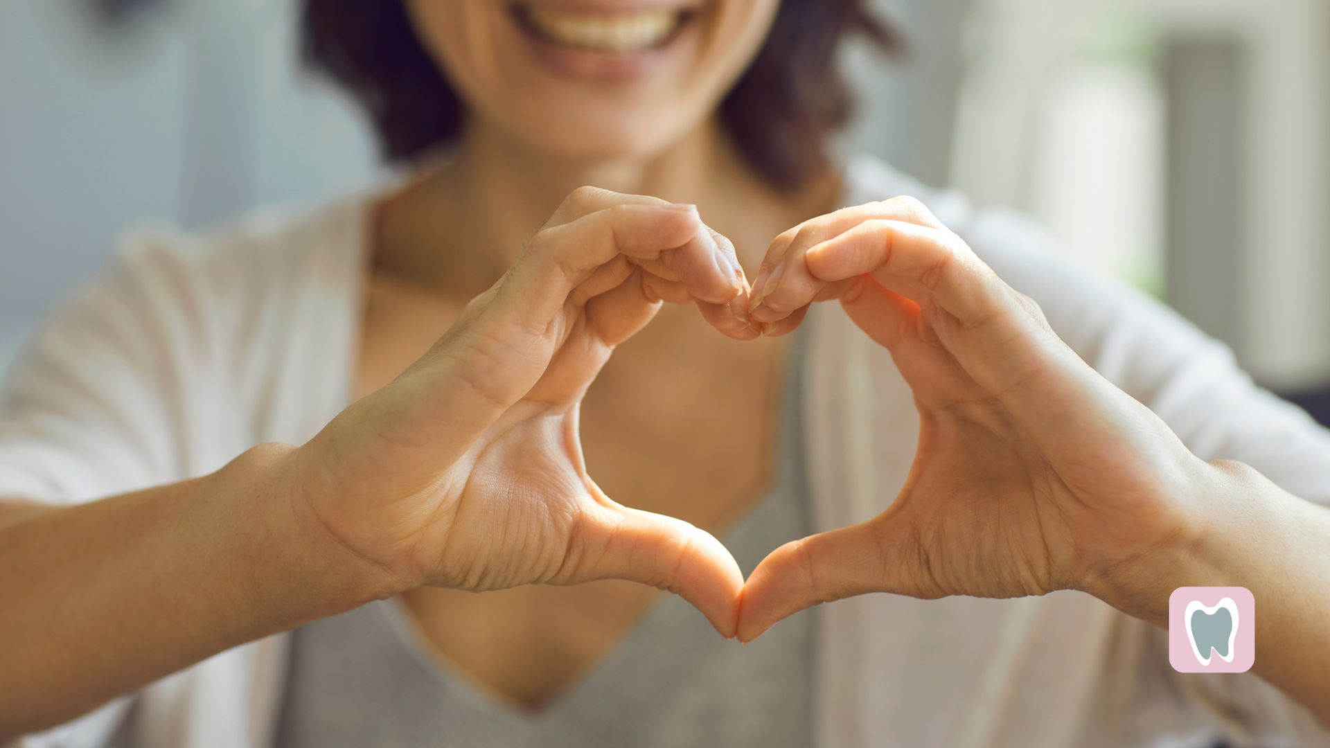 A woman is making a heart shape with her hands.