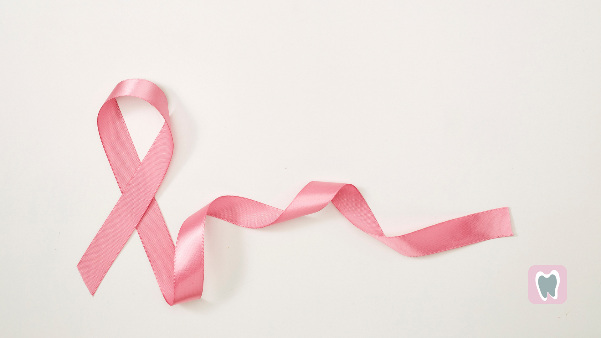 A pink ribbon is laying on a white surface.