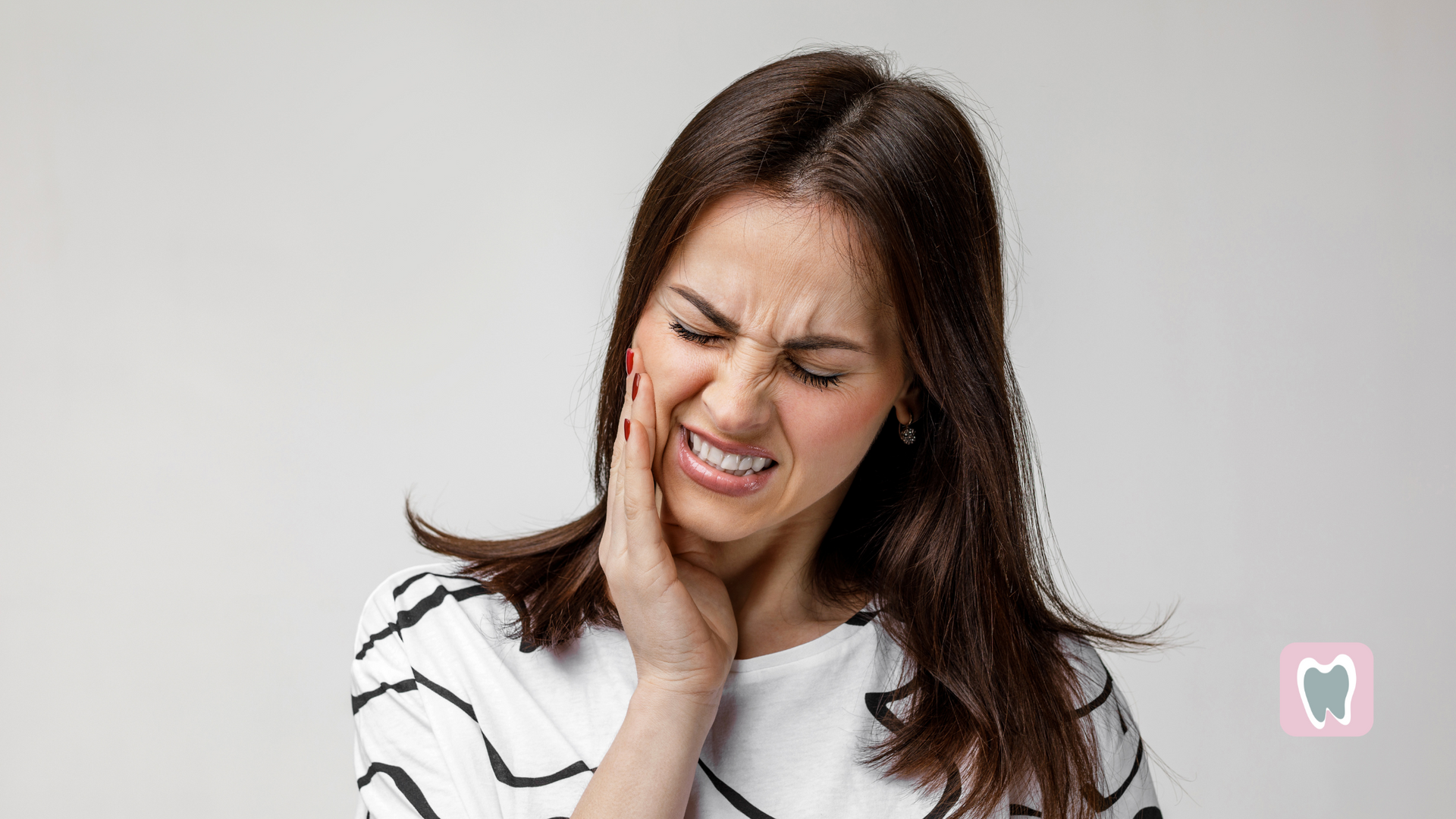 A woman is holding her face in pain because of a toothache.