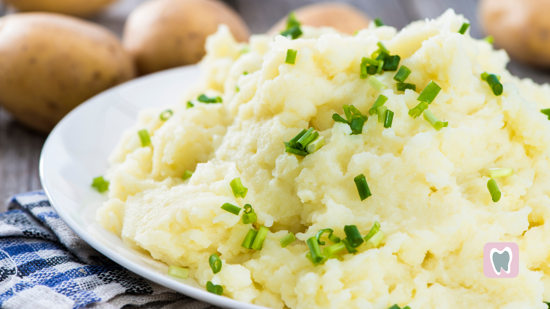 A white plate topped with mashed potatoes and green onions.