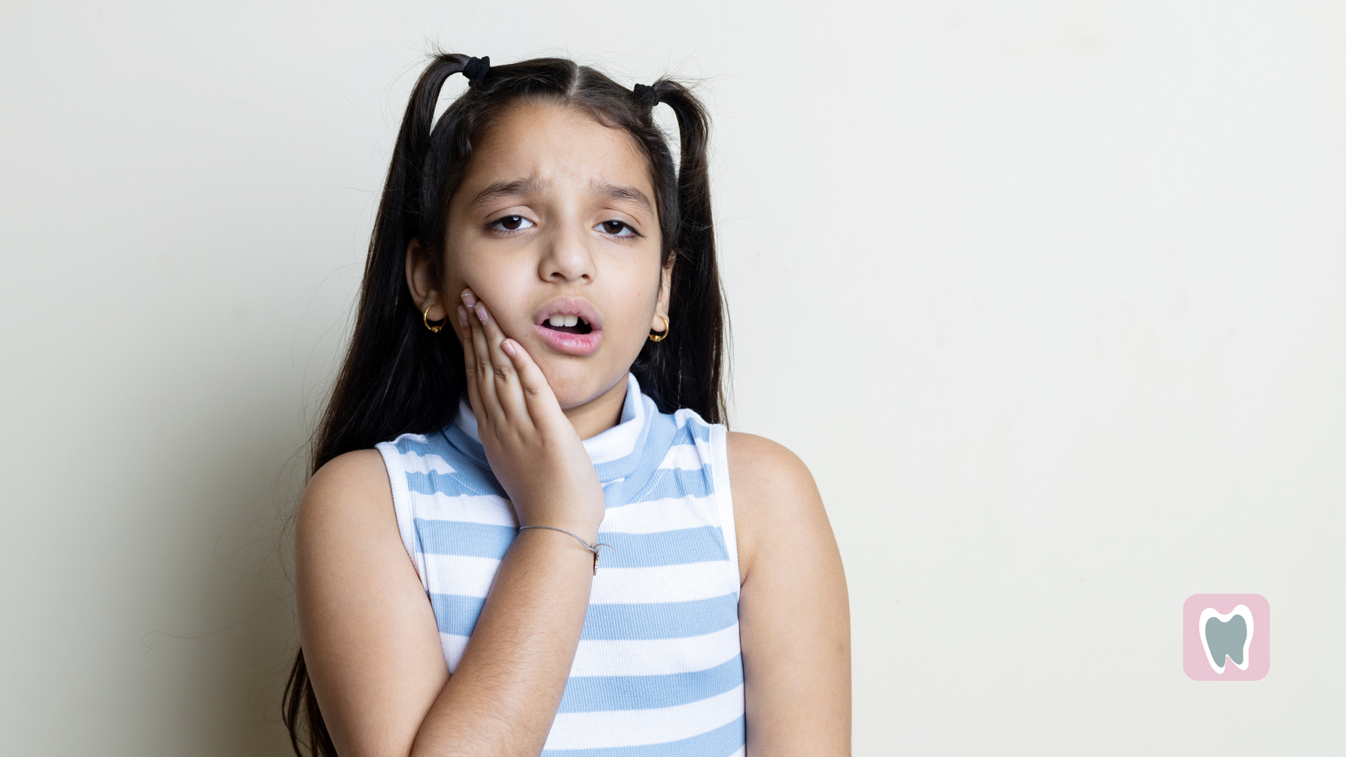 A young girl is holding her face in pain because of a toothache.