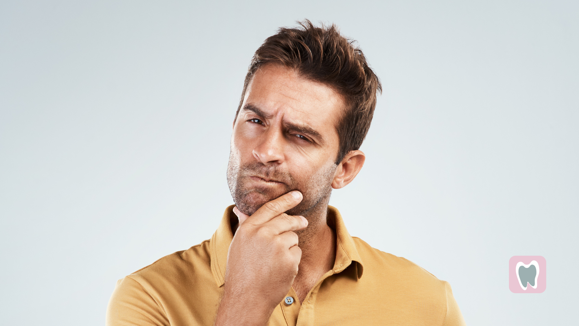 Man with a questioning expression, hand on chin, looking at viewer.