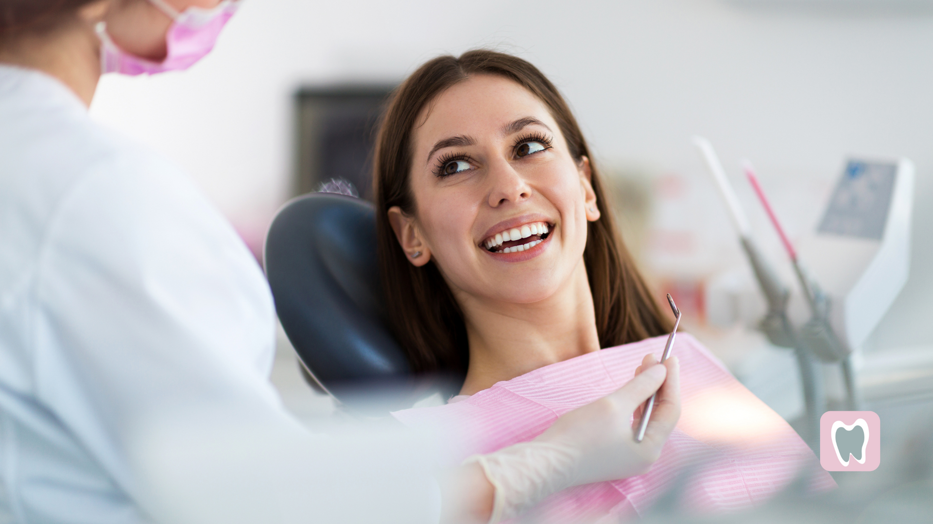 A woman is smiling while sitting in a dental chair.