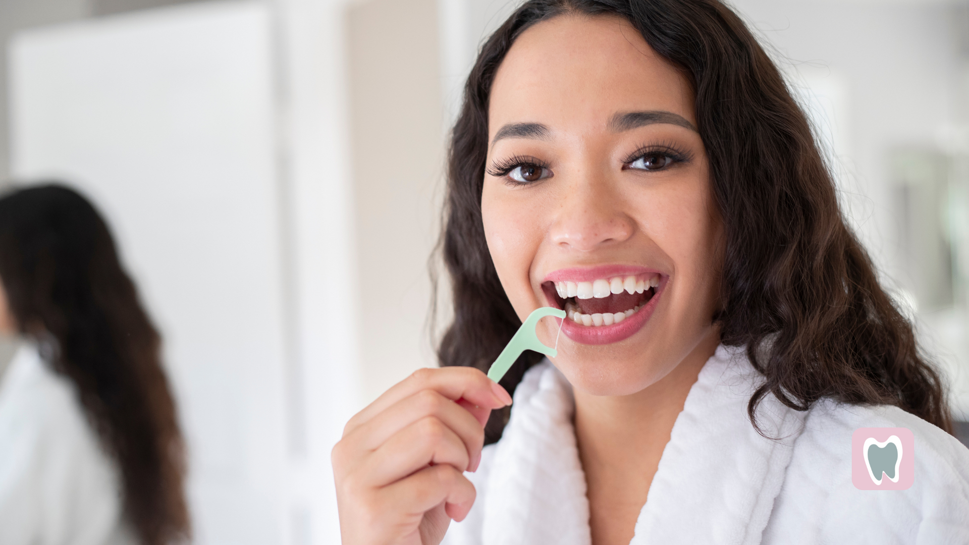 A woman is brushing her teeth with an interdental brush in front of a mirror.
