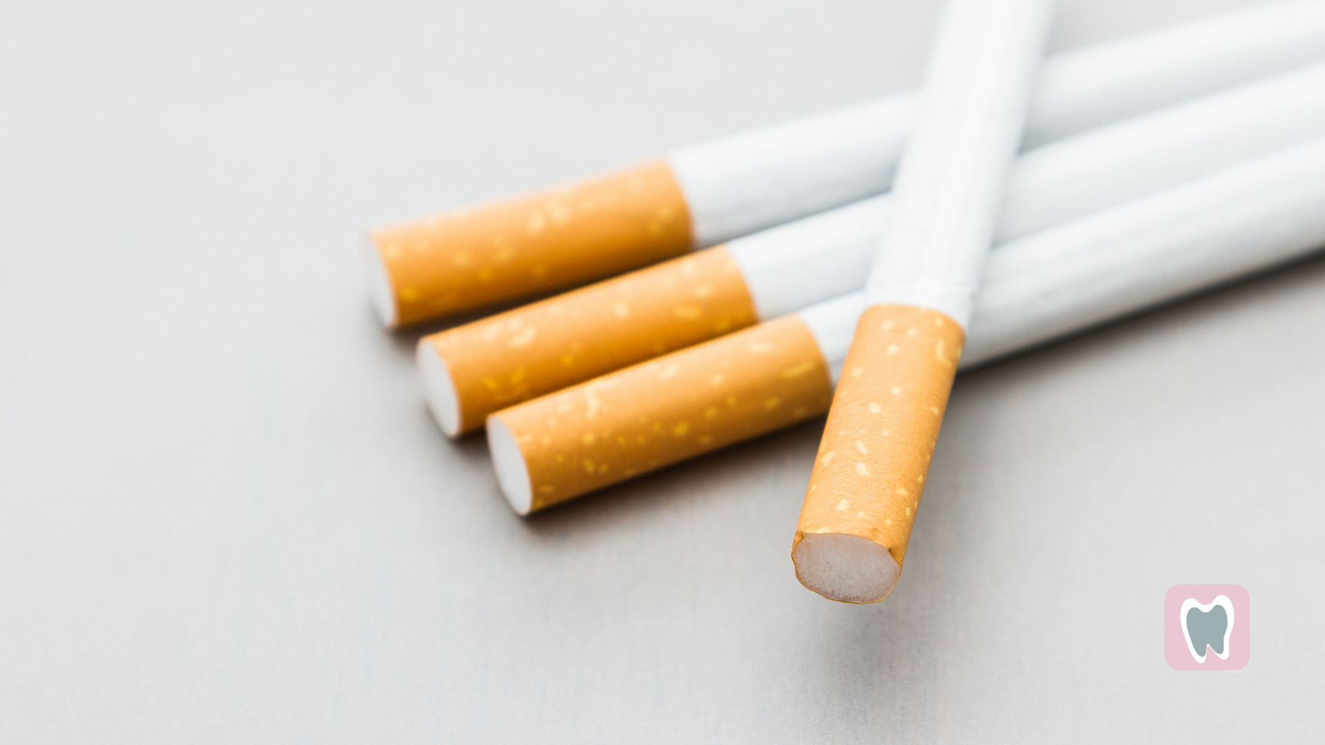 Three cigarettes are stacked on top of each other on a table.