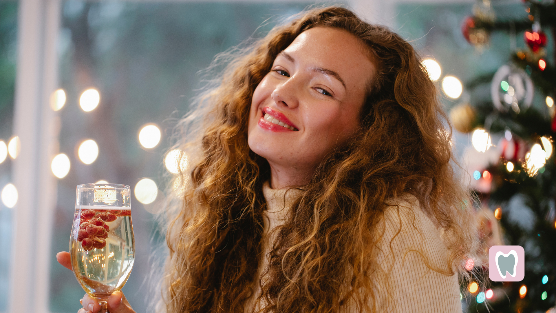 A woman is holding a glass of champagne in front of a christmas tree.