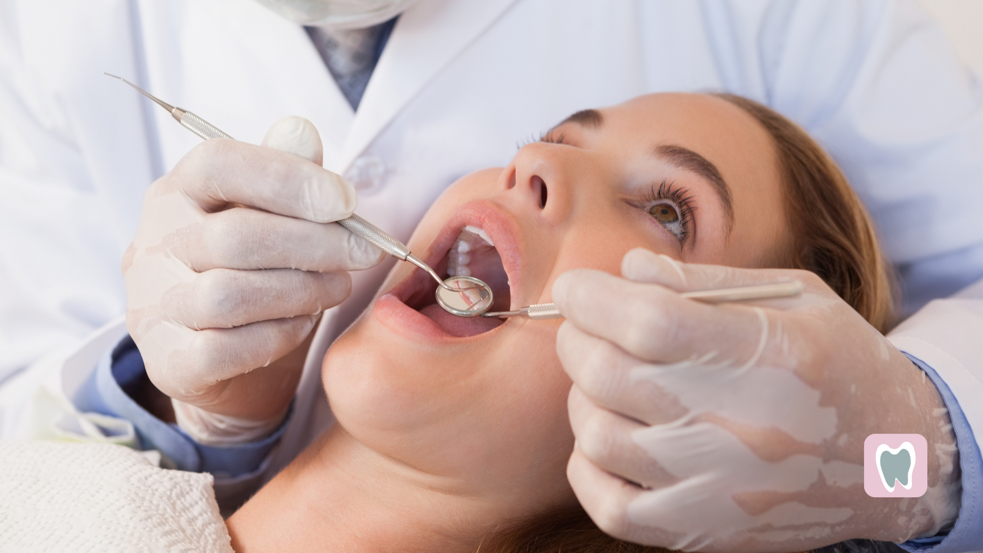 Dentist examining a woman's teeth with dental tools in a clinic.