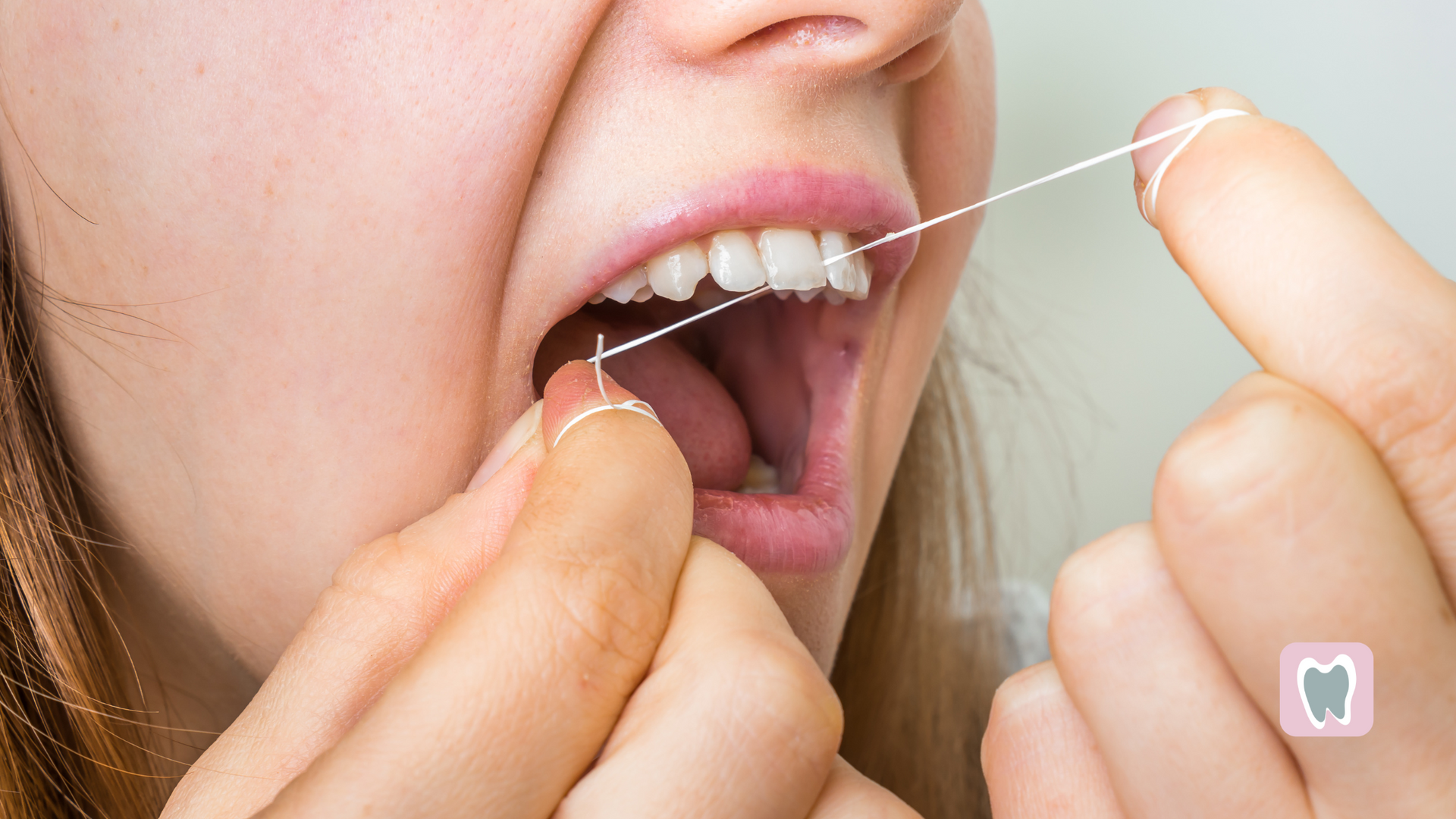 A woman is flossing her teeth with a dental floss.