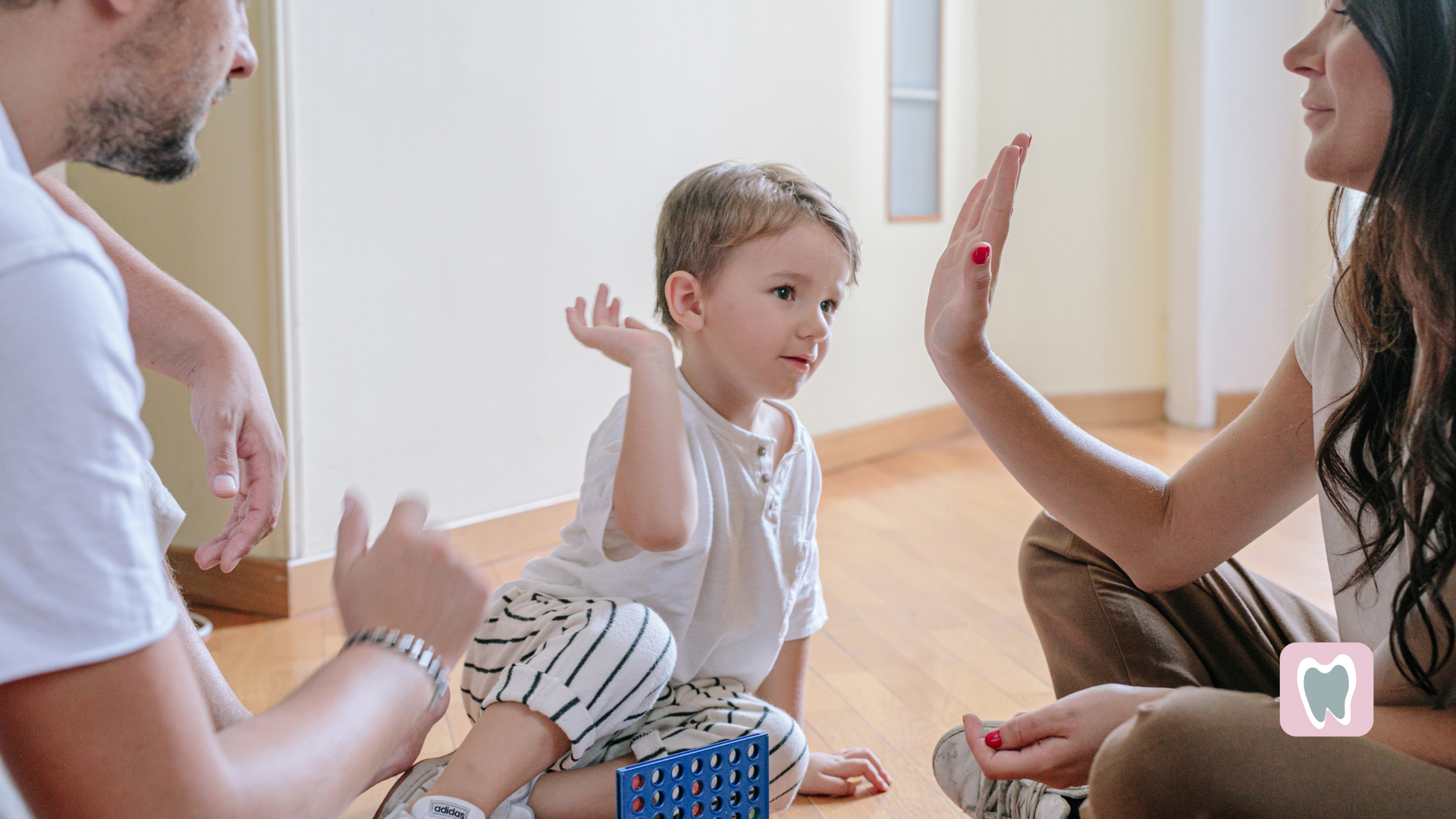 A family is sitting on the floor giving each other a high five.