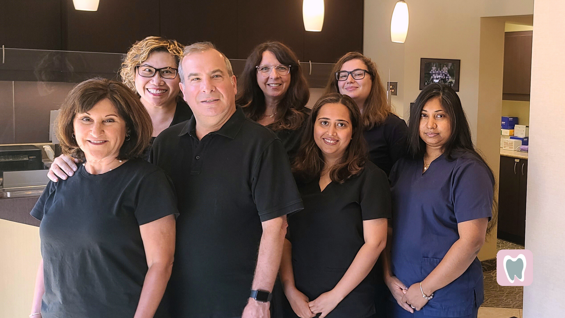 A group of people are posing for a picture in a dental office.