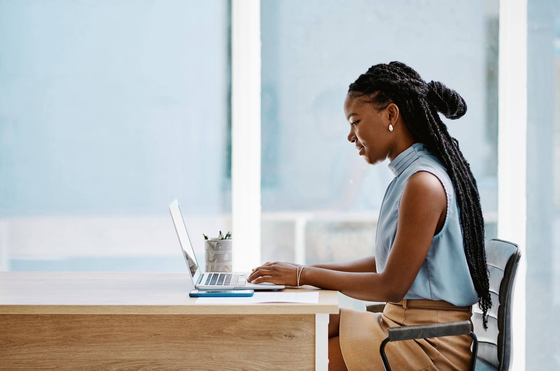 A woman is sitting at a desk using a laptop computer.