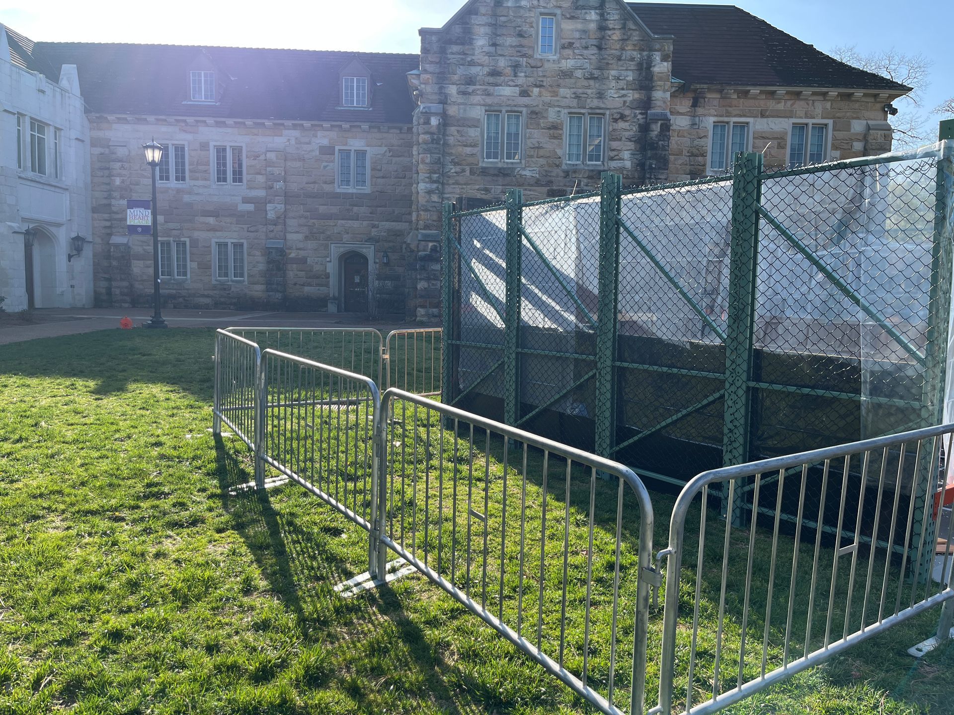 A fence is surrounding a grassy area in front of a building.