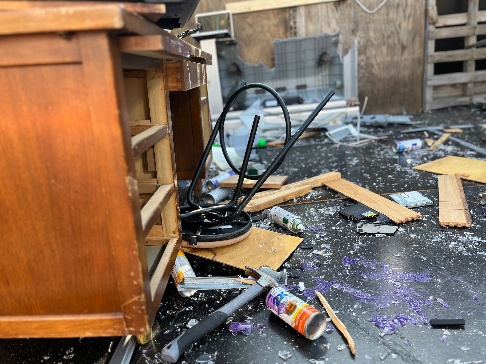 A messy room with a wooden cabinet and a bottle of glue on the floor.
