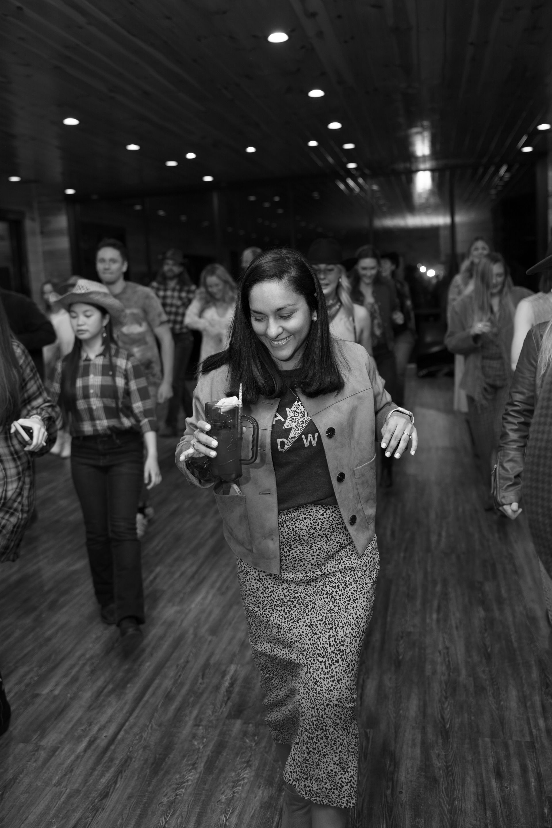 A woman is dancing in a black and white photo with a group of people.