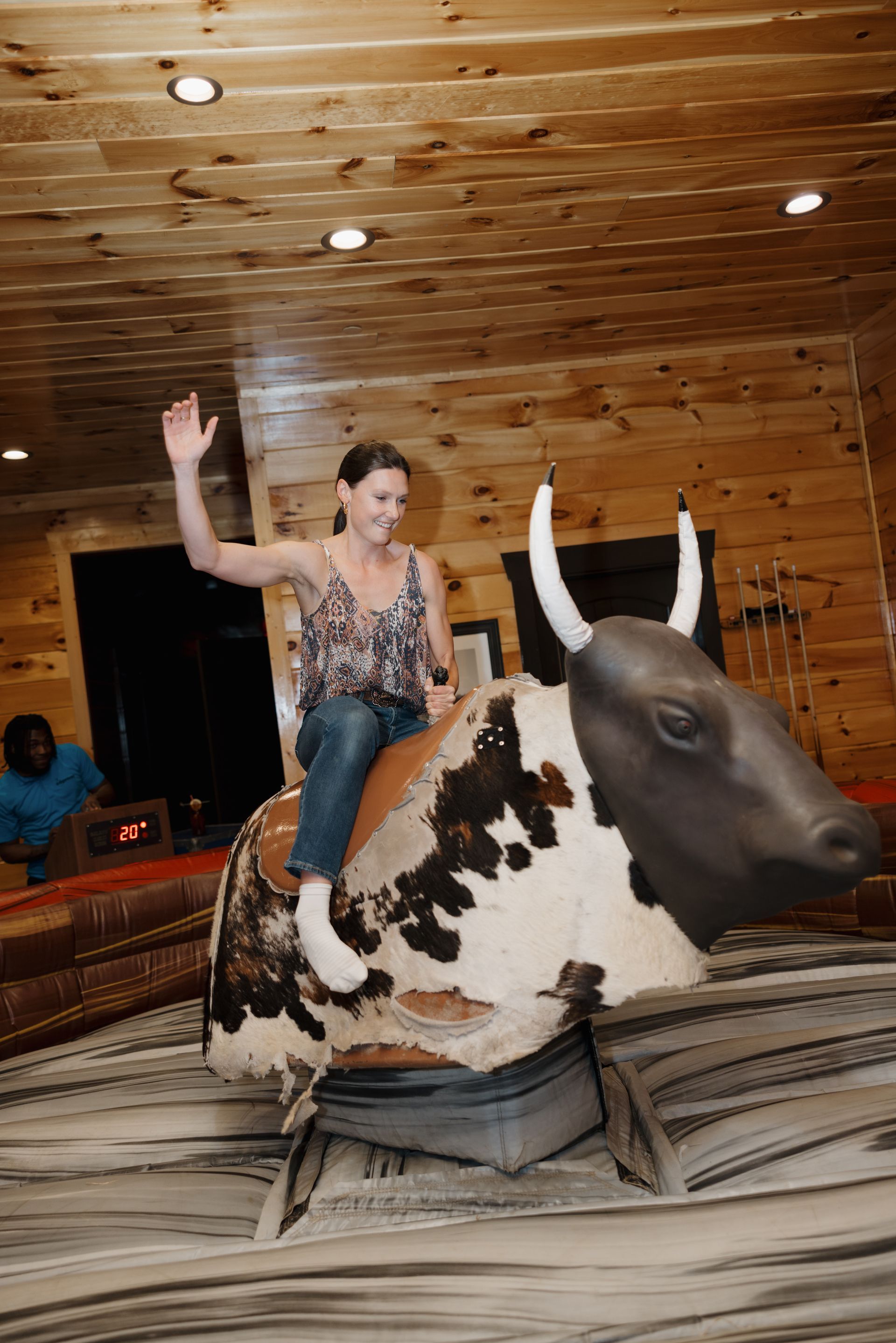 A woman is riding a mechanical bull in a living room.