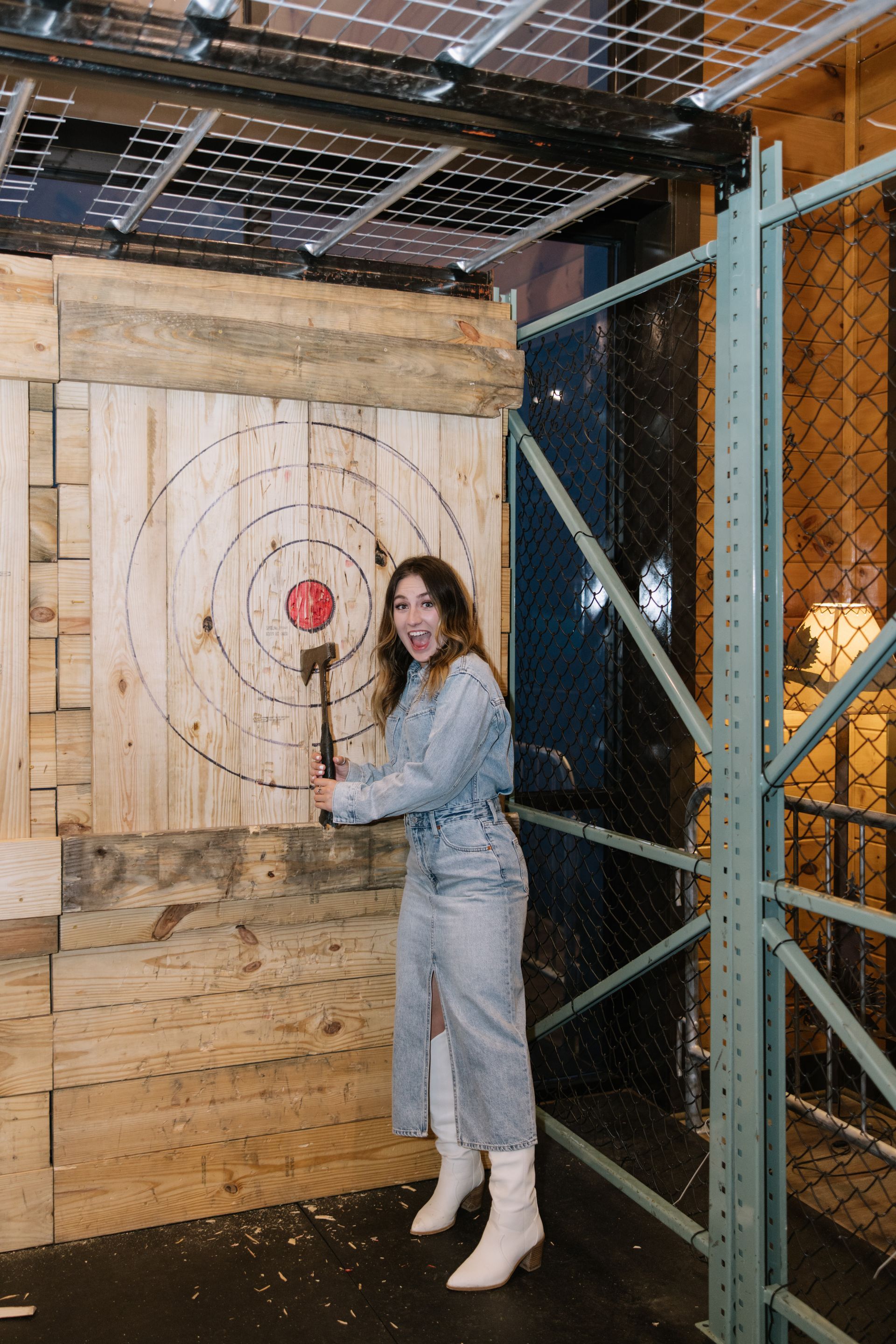 A woman is holding a hammer in front of a target.
