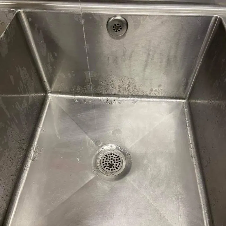 A close up of a stainless steel sink with a drain.