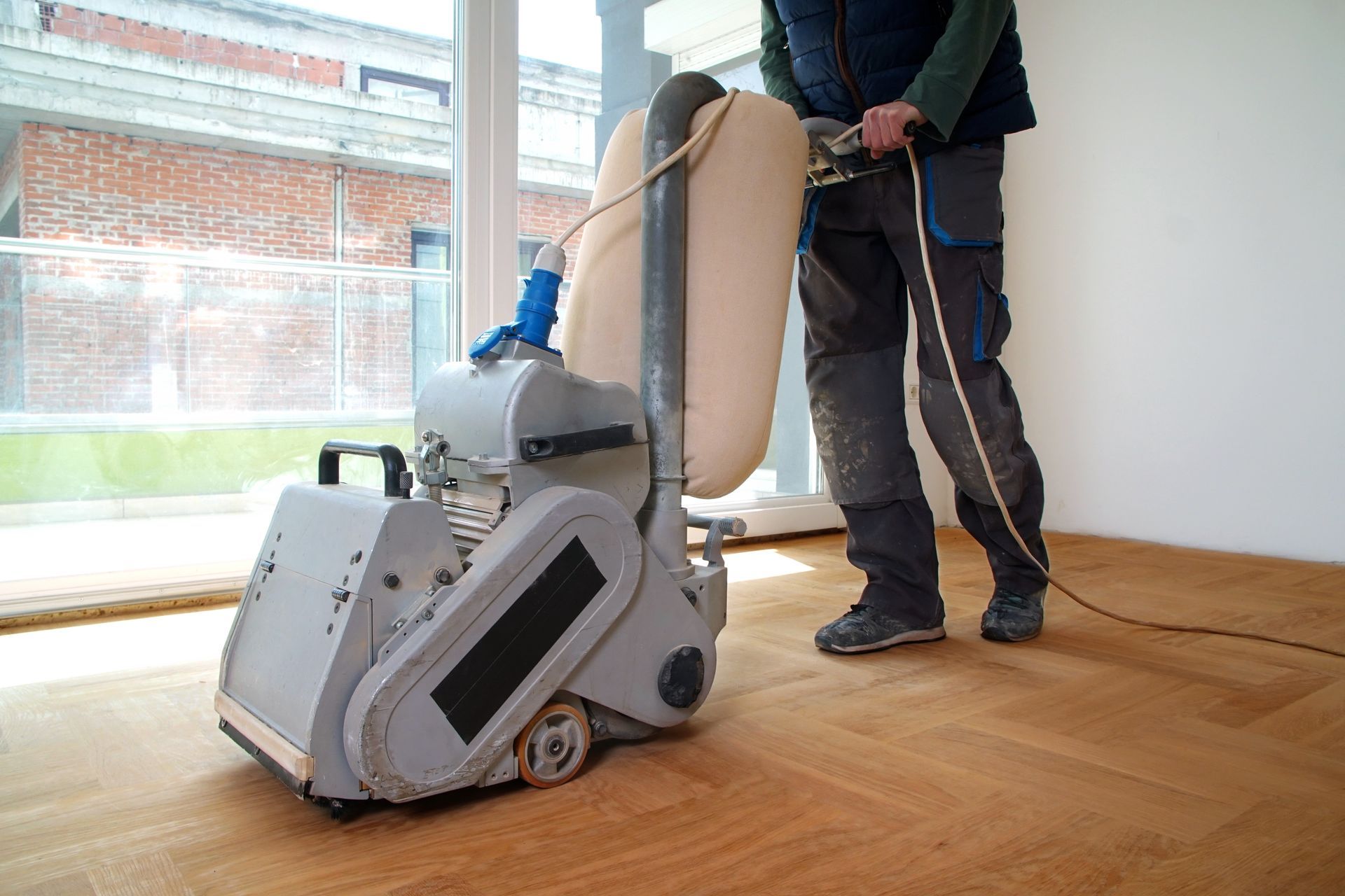 A man is sanding a wooden floor with a machine.