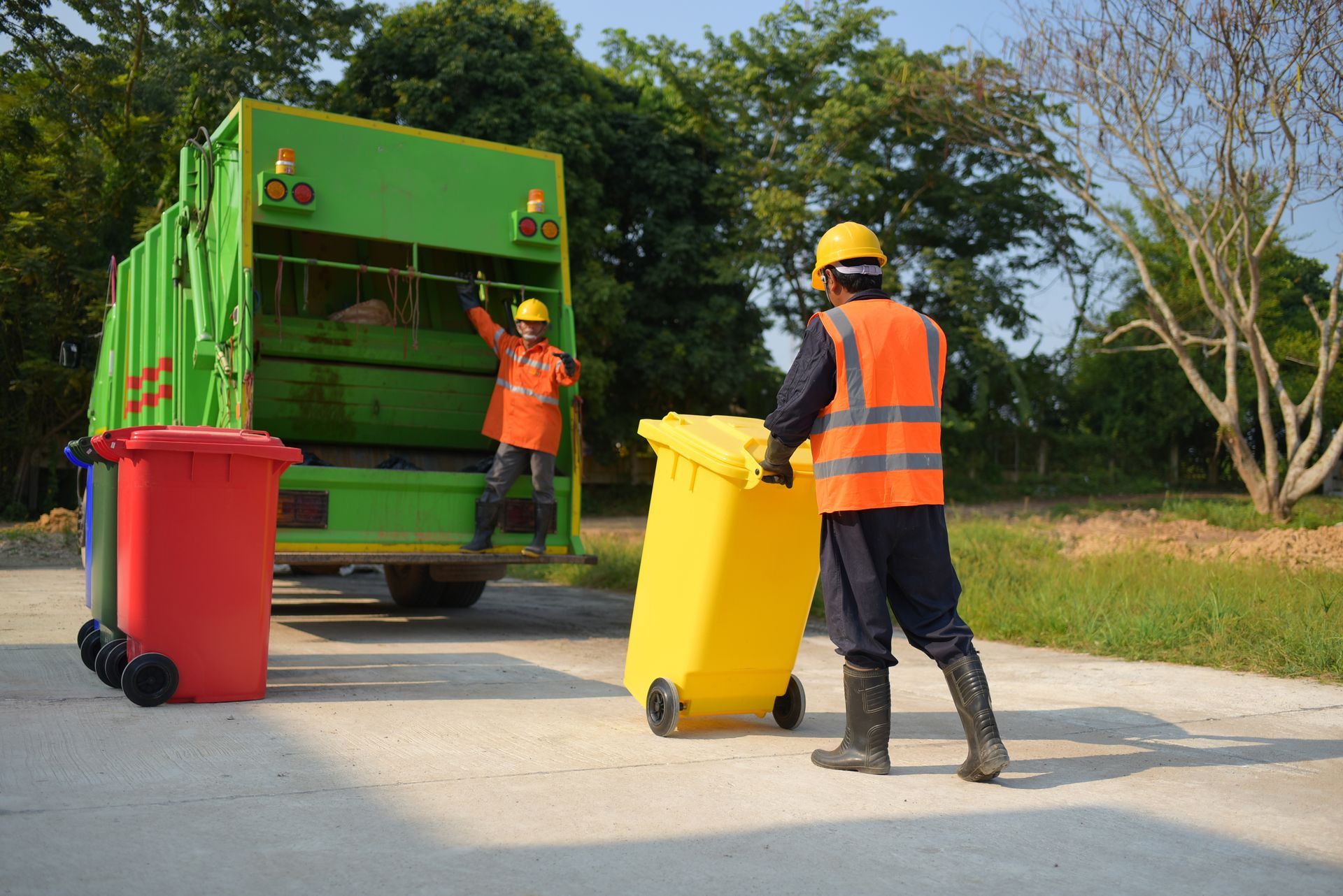 A man is loading a yellow trash can into a garbage truck.