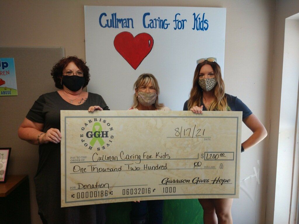 A large check being gifted to cullman caring for kids worth $1200
