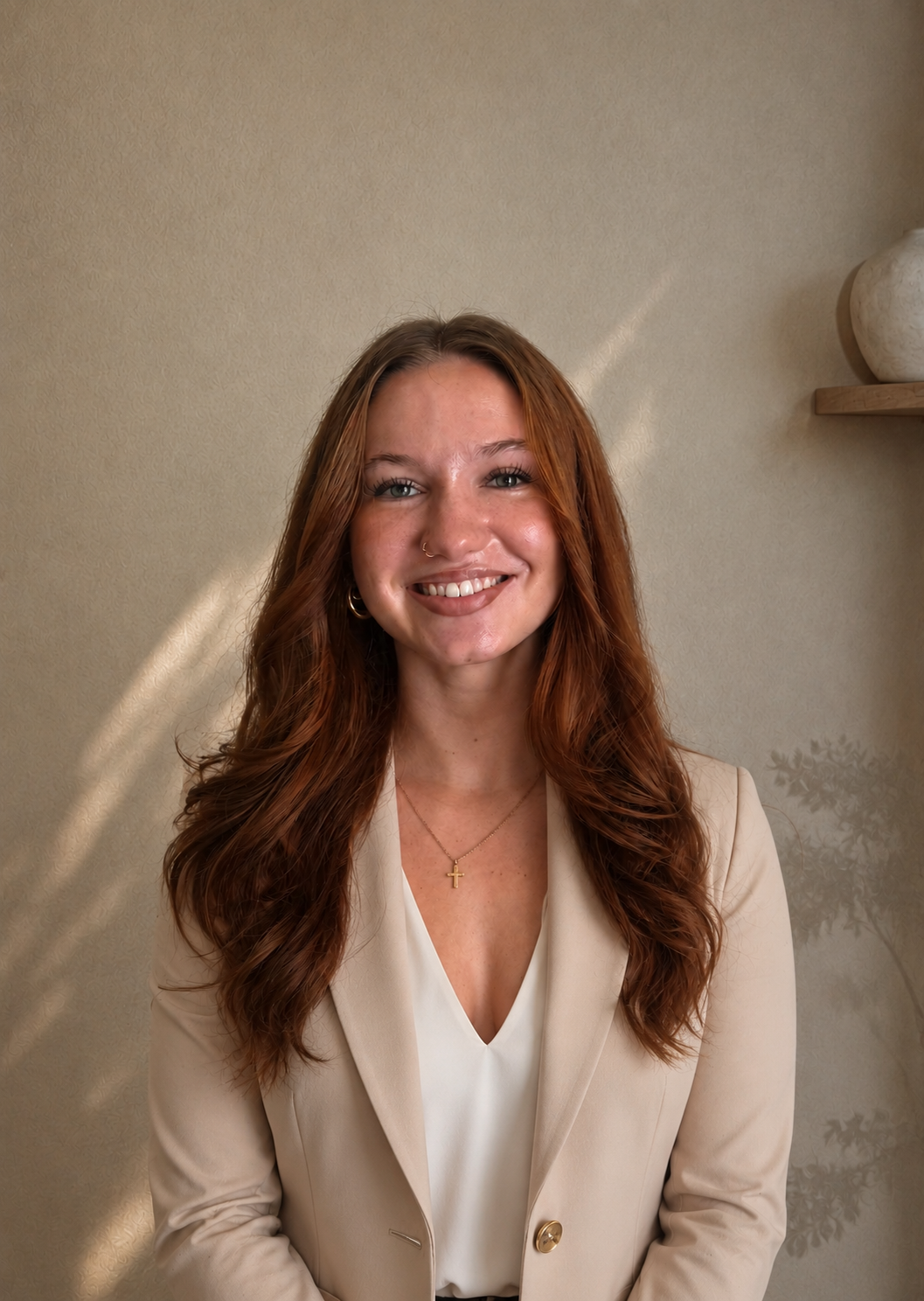 Smiling woman in a beige blazer against a neutral wall
