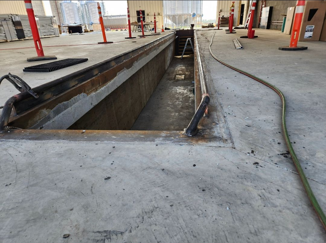 Construction site with open trench in concrete floor and hoses running beside it