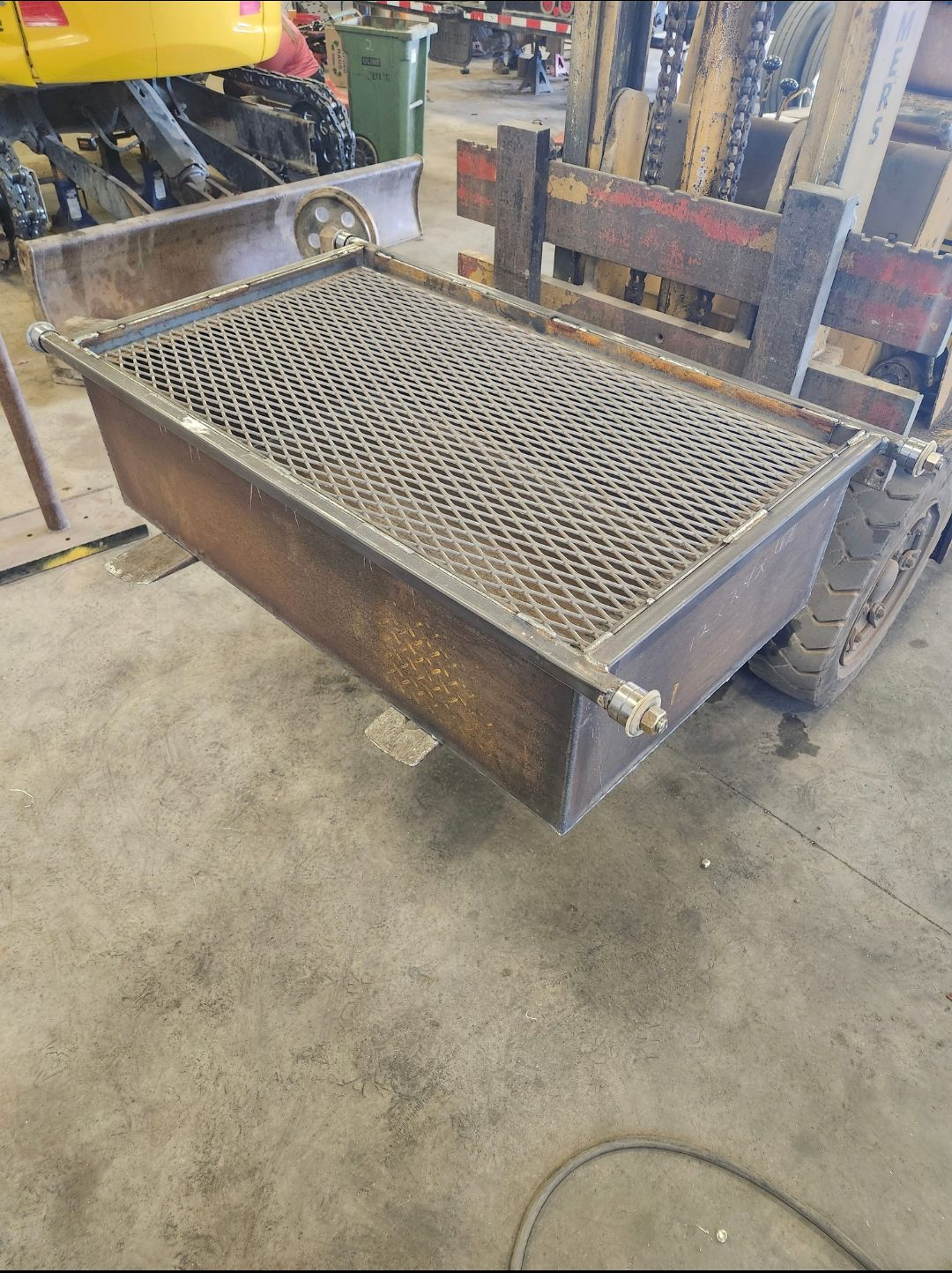 Metal industrial hopper or bin with a grated top in a workshop setting