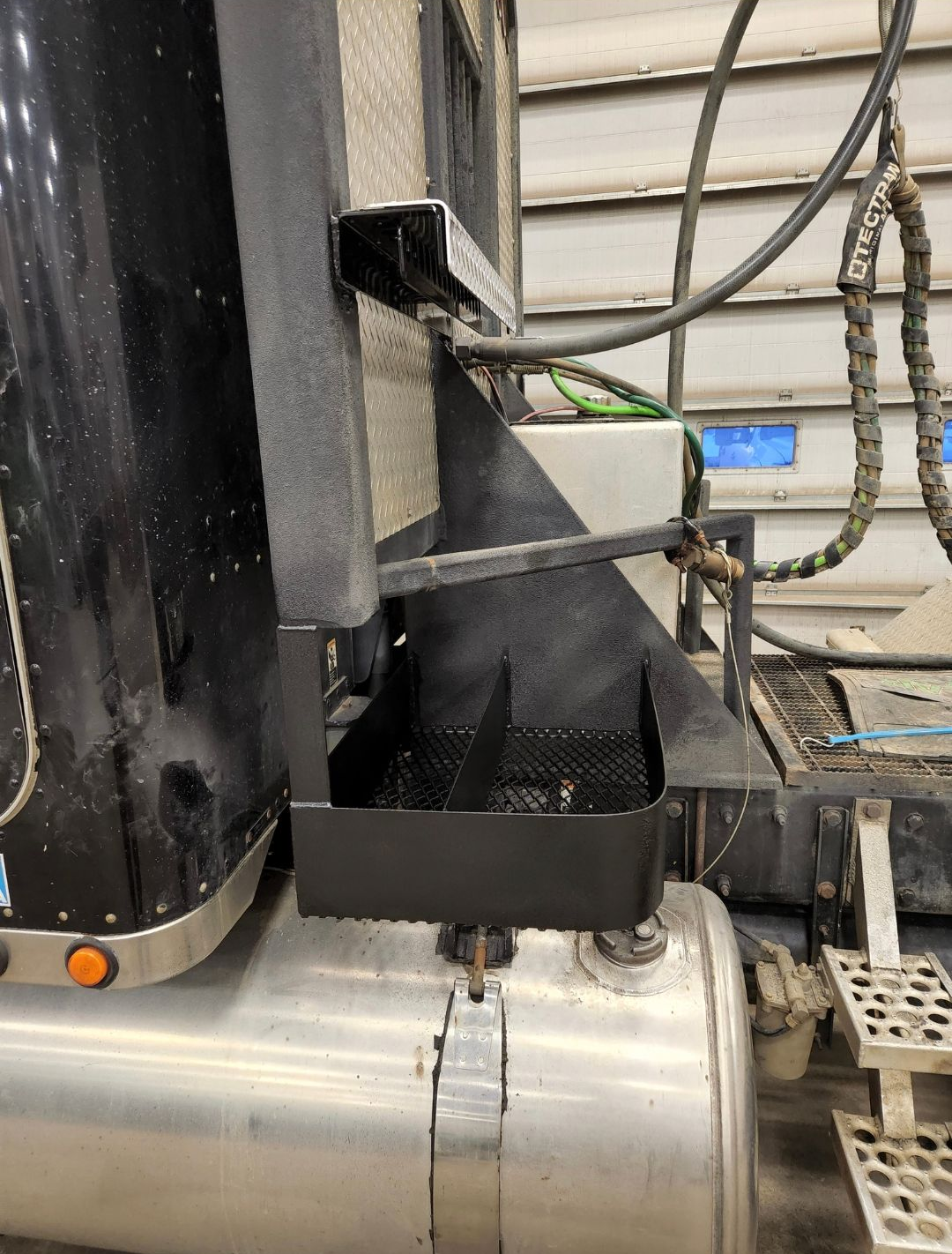 Industrial machine close-up with black metal frame over silver ducting and hanging cables
