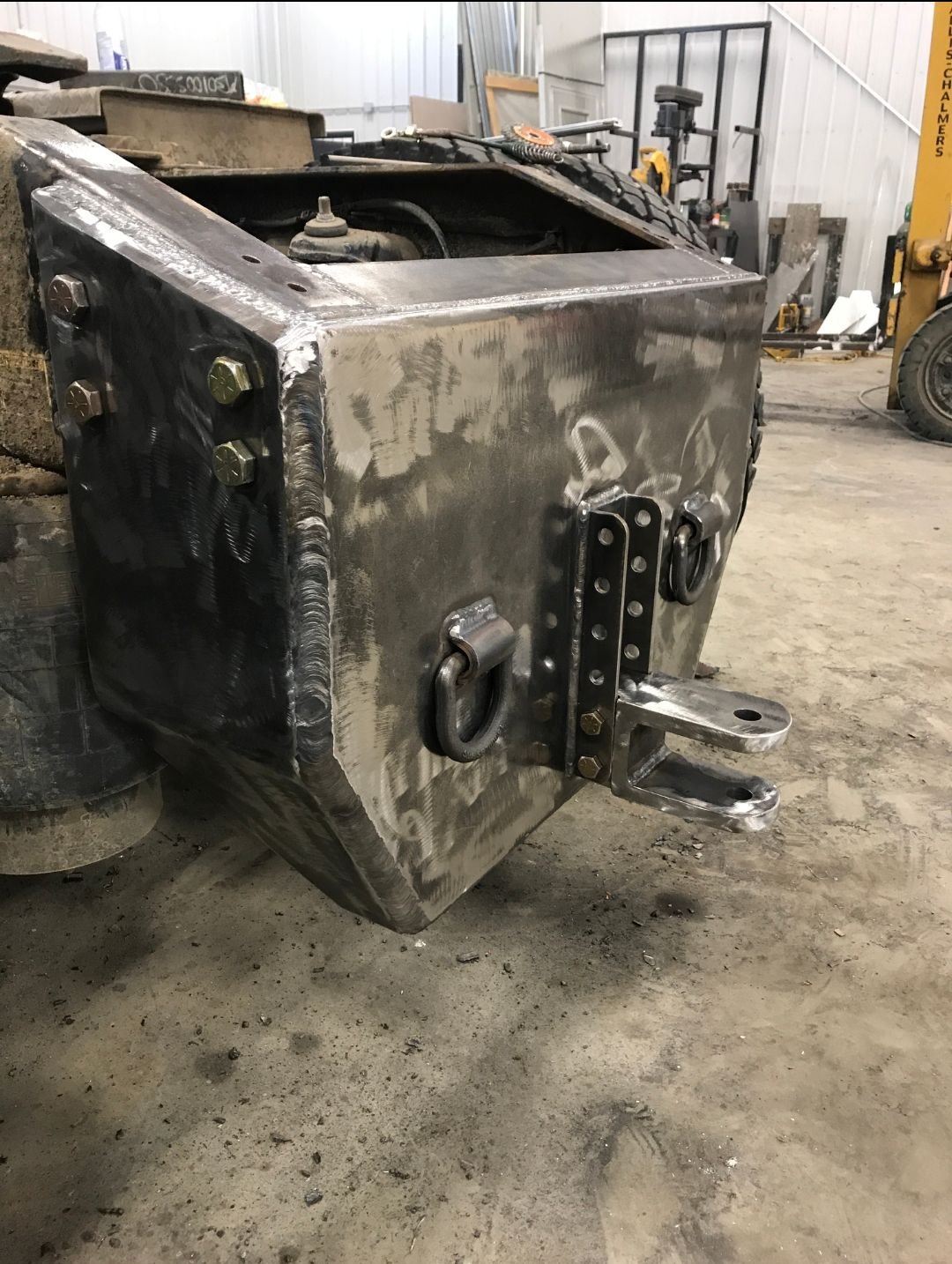 Large black metal industrial machine housing in a workshop, with rust and mounting brackets visible