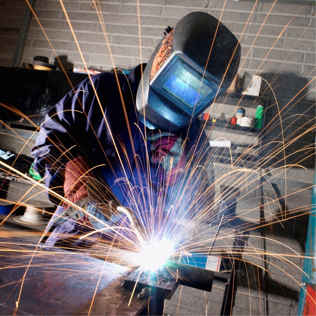 Welder in protective helmet creating bright sparks in a workshop