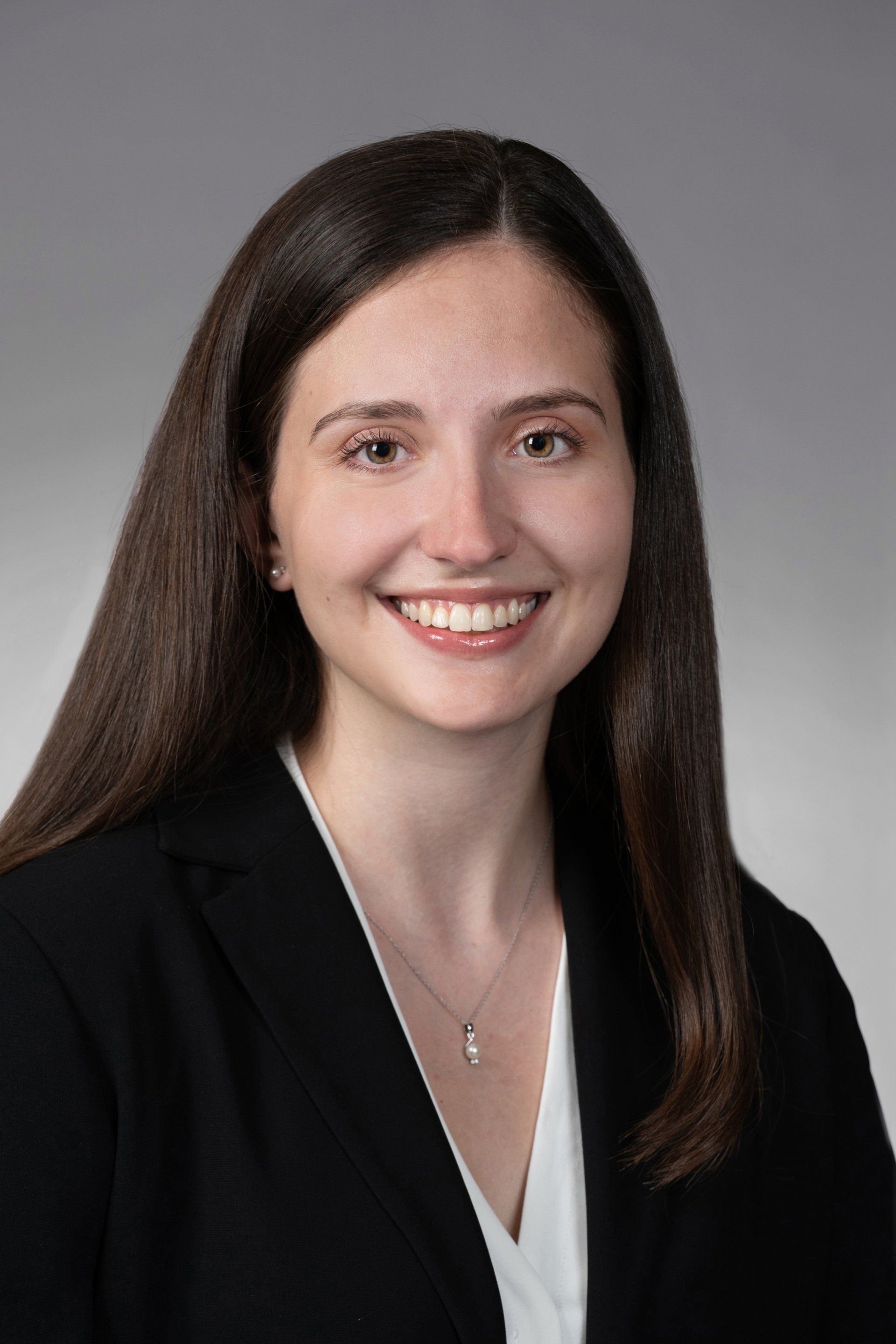 A woman in a black jacket and white shirt is smiling for the camera.