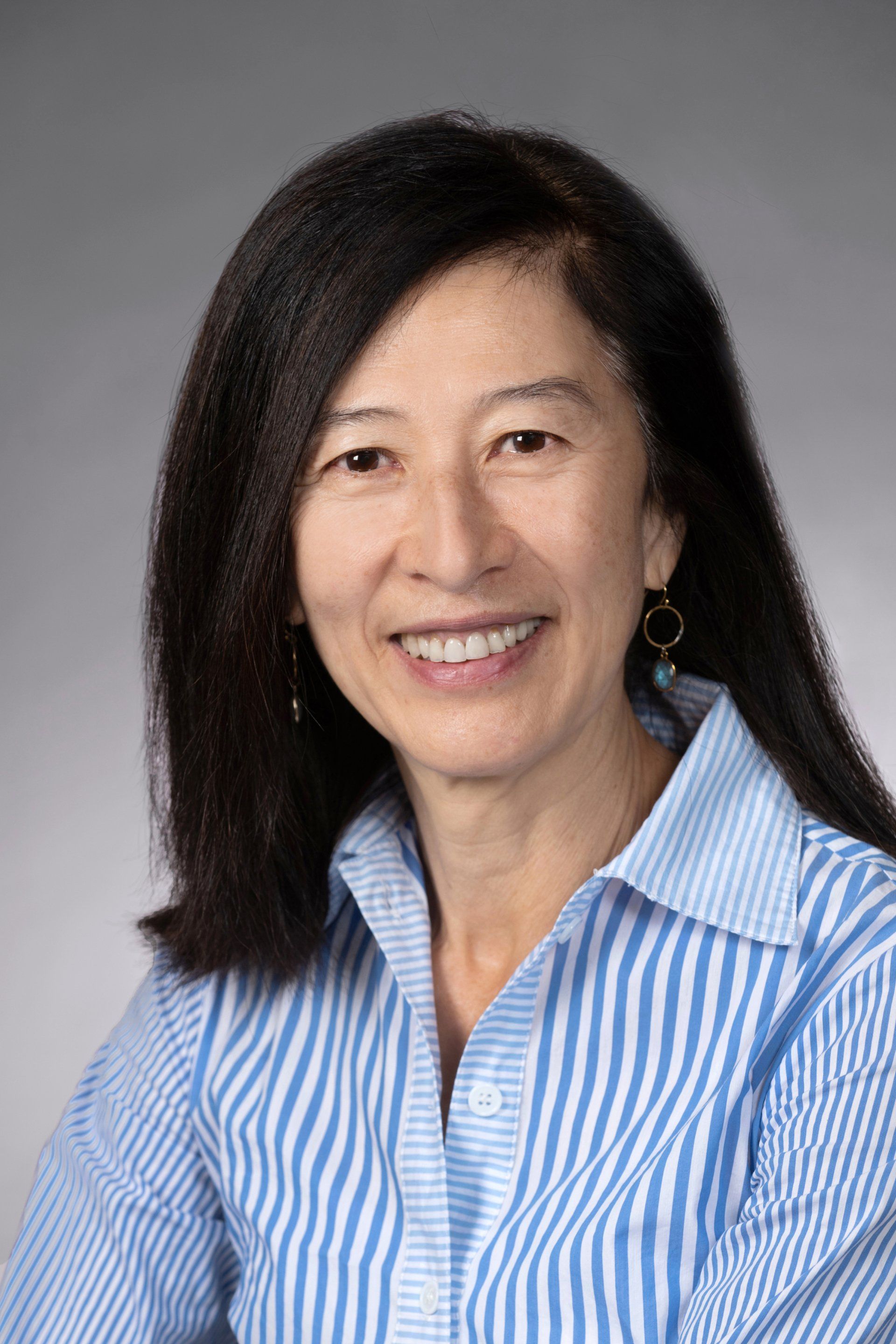 A woman in a blue and white striped shirt is smiling for the camera.
