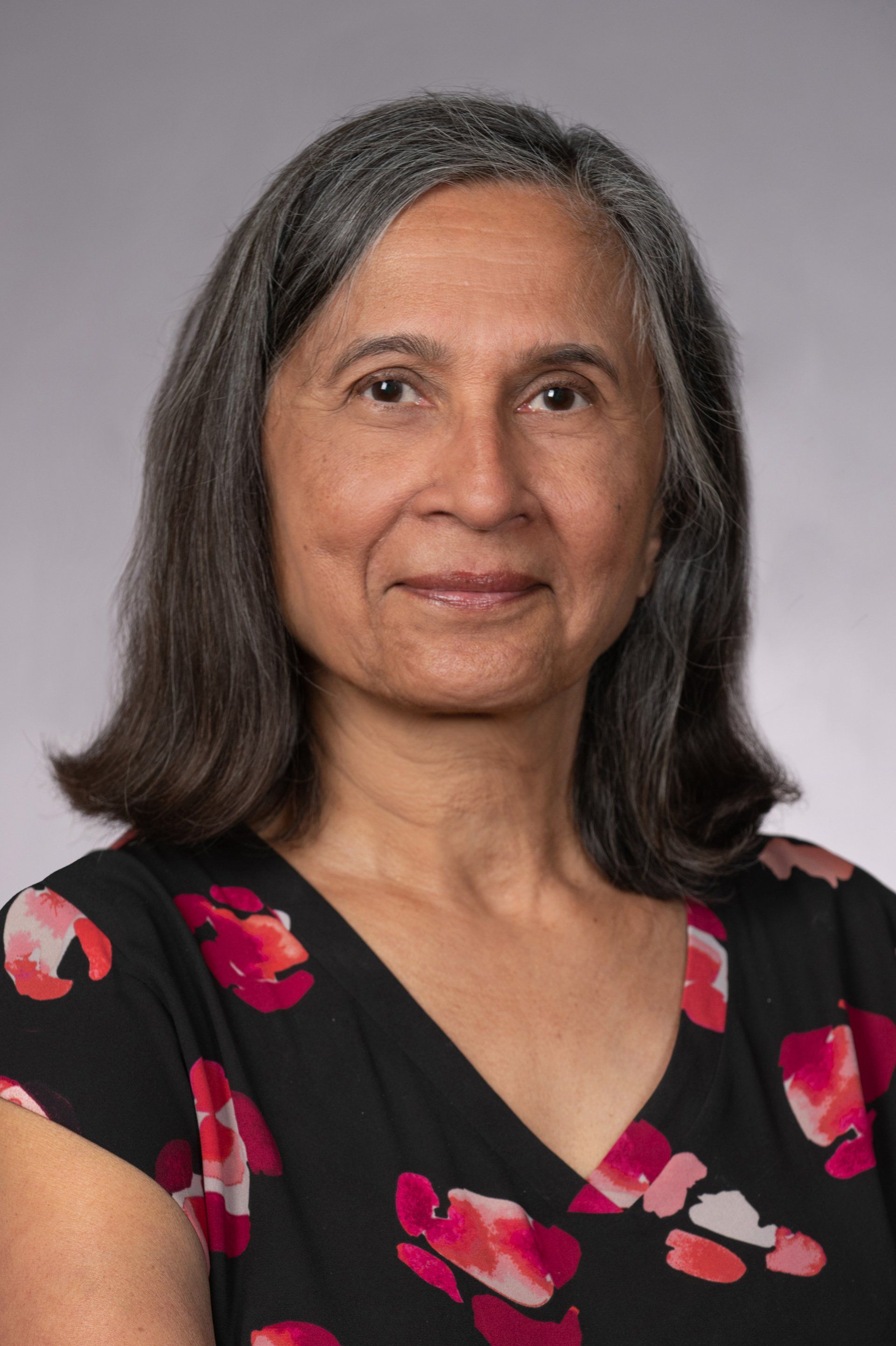 A woman in a floral dress is smiling for the camera.