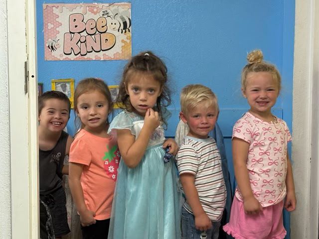 Five children smiling in a doorway, with a 