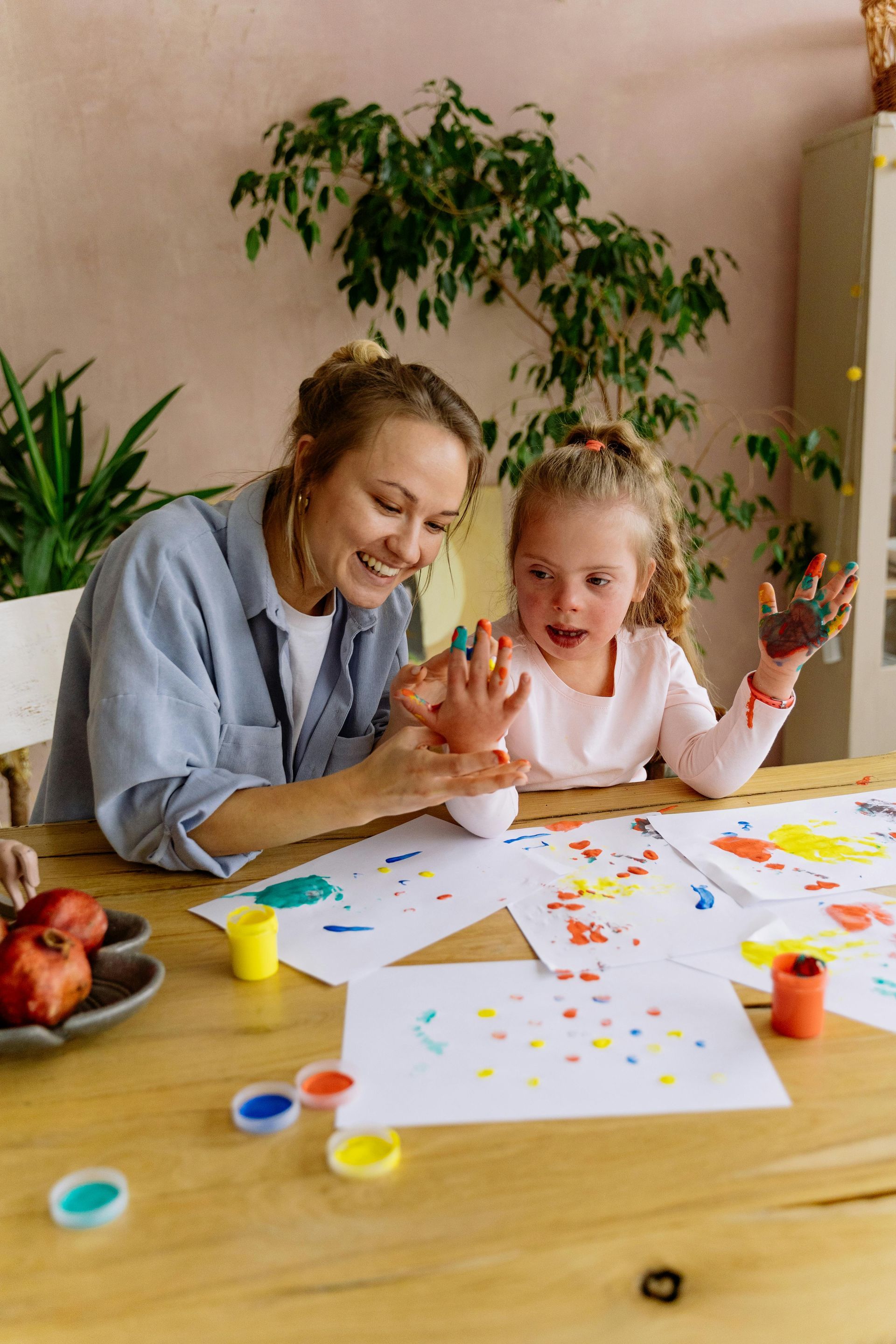Two people painting at a table with colorful art supplies in a bright room