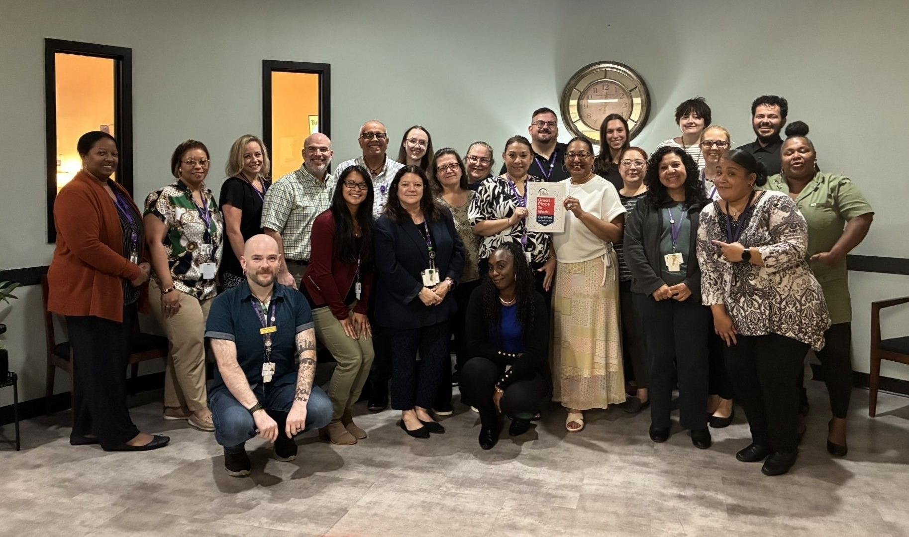 A large group of BHN staff posing with a image of the Great Place to Work Certification logo.