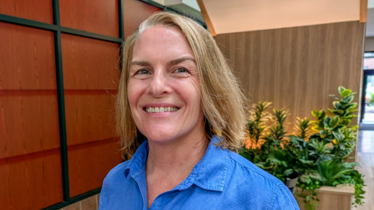 Dr.Potee smiles for a photo in an office that has plants and wooden panels behind her.
