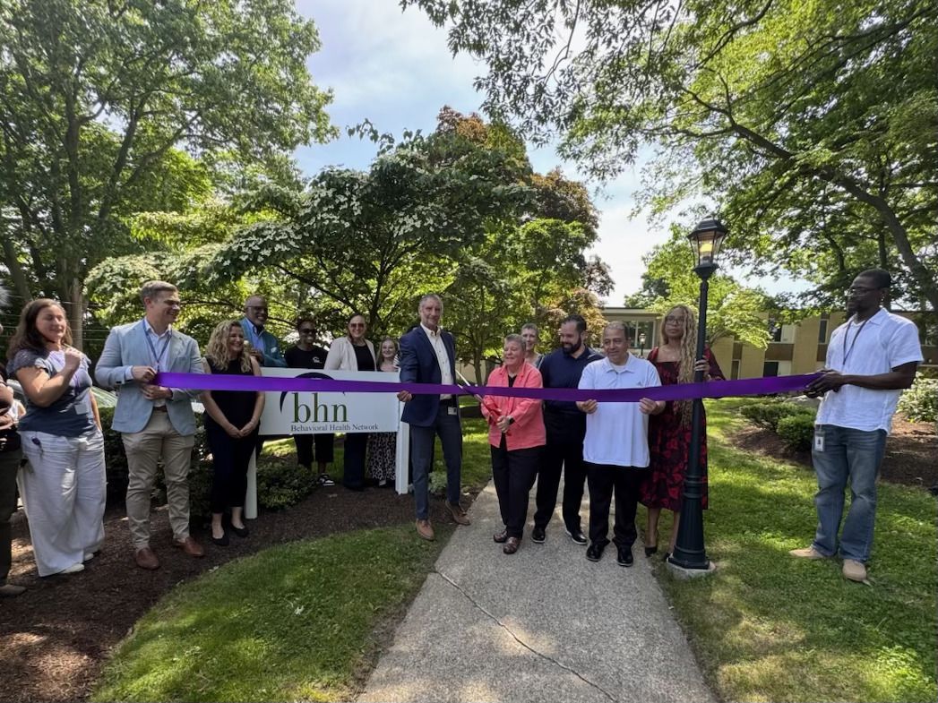A group gathers as Rose cuts the ribbon in front of the BHN sign.