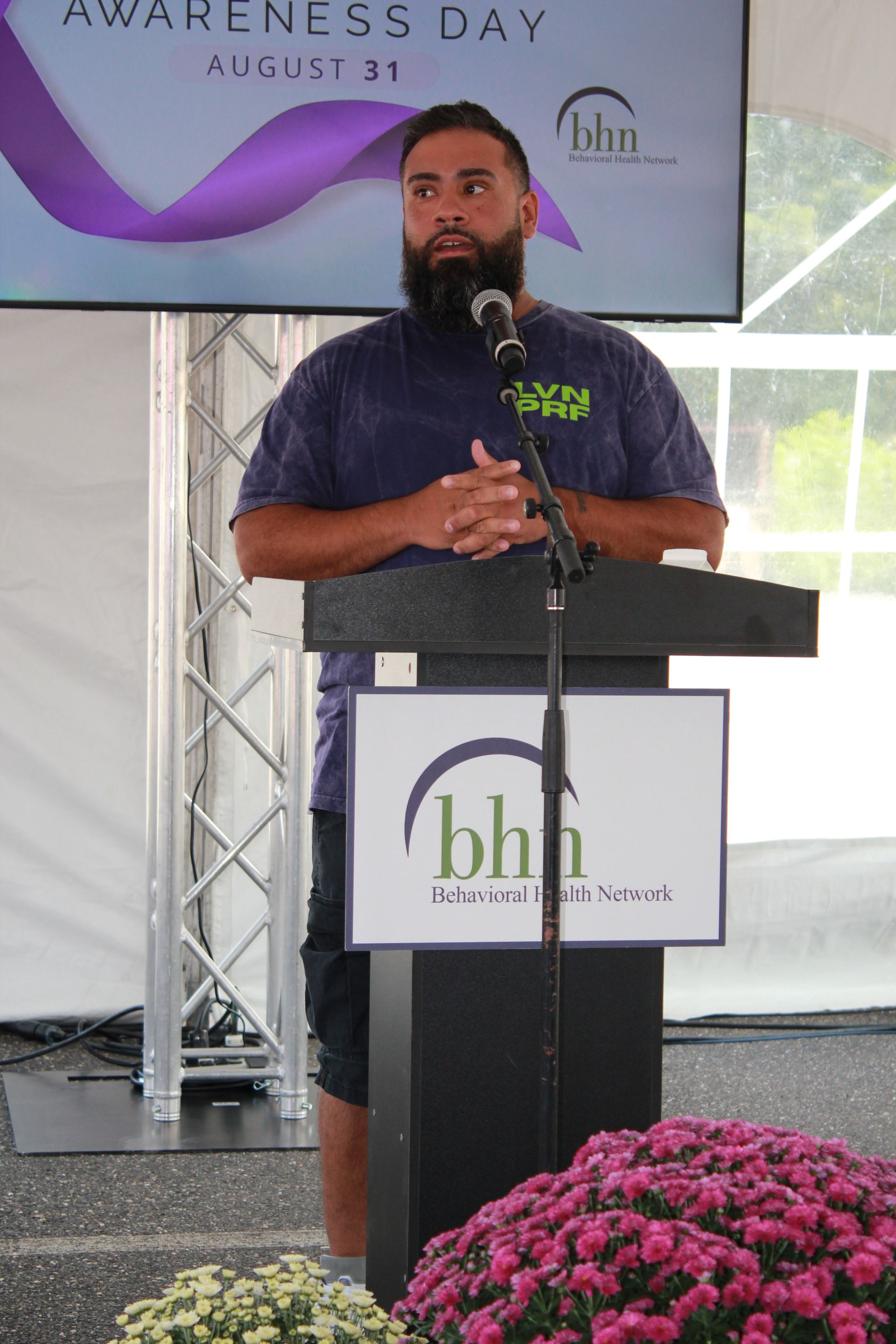 A man smiles gives a speech at a podium for BHN's International Overdose Awareness Day event. 