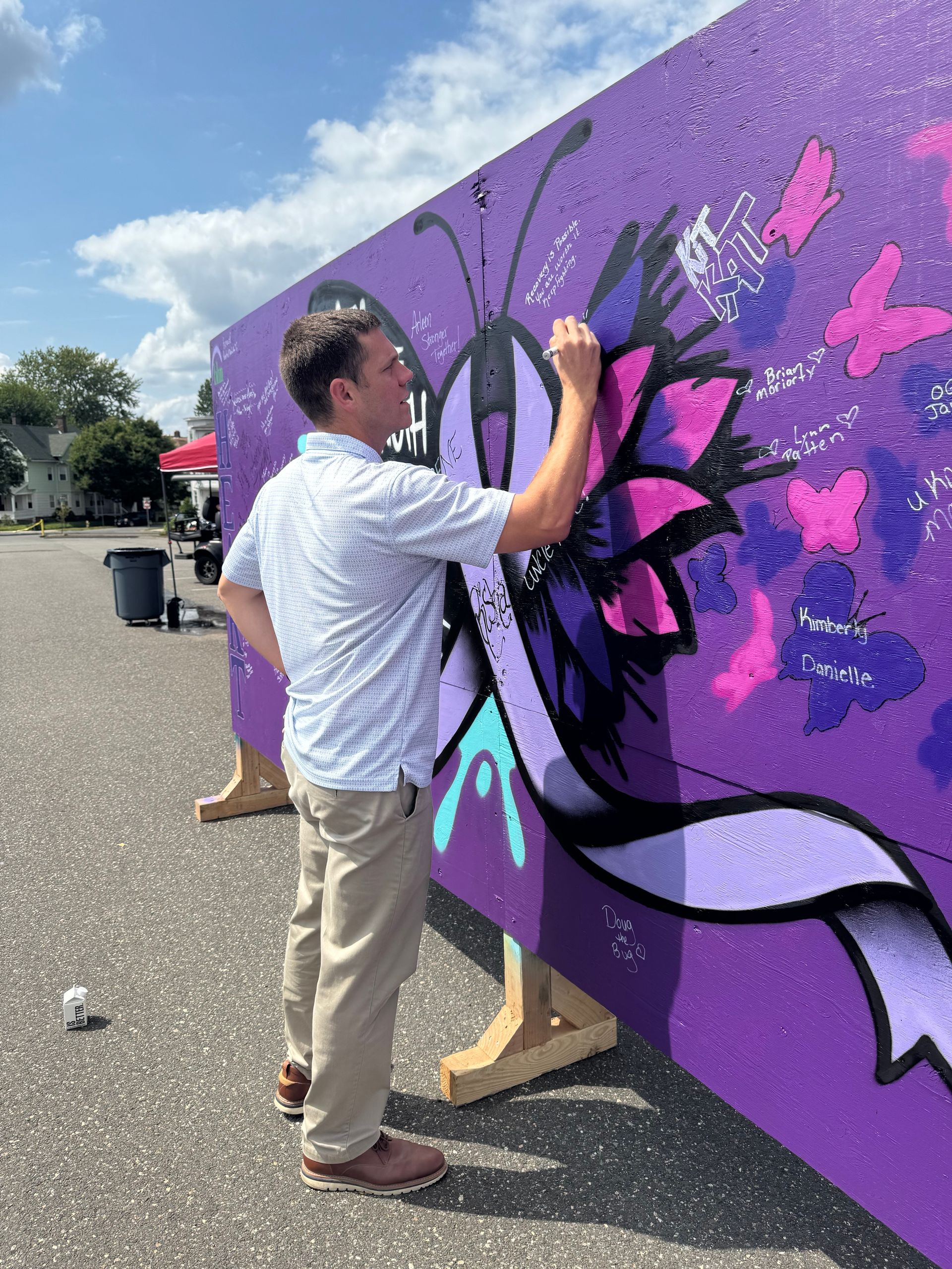 Senator Velis writes positive affirmations on a purple board for International Overdose Awareness Day.