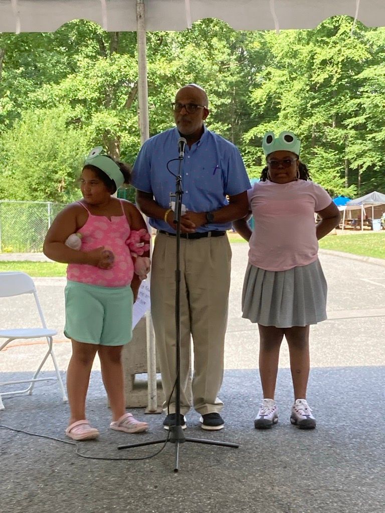 BHN Senior Vice President Tony Boswell delivers a speech at the Kamp for Kids opening day with two Kampers standing beside him.