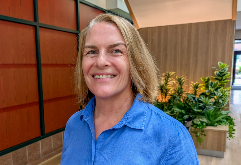 Dr.Potee smiles for a photo in an office that has plants and wooden panels behind her.