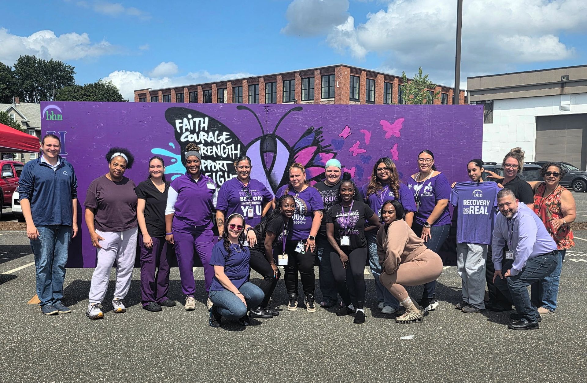 BHN's Recovery Coaches pose for a group photo in front of a purple board for International Overdose Awareness Day.