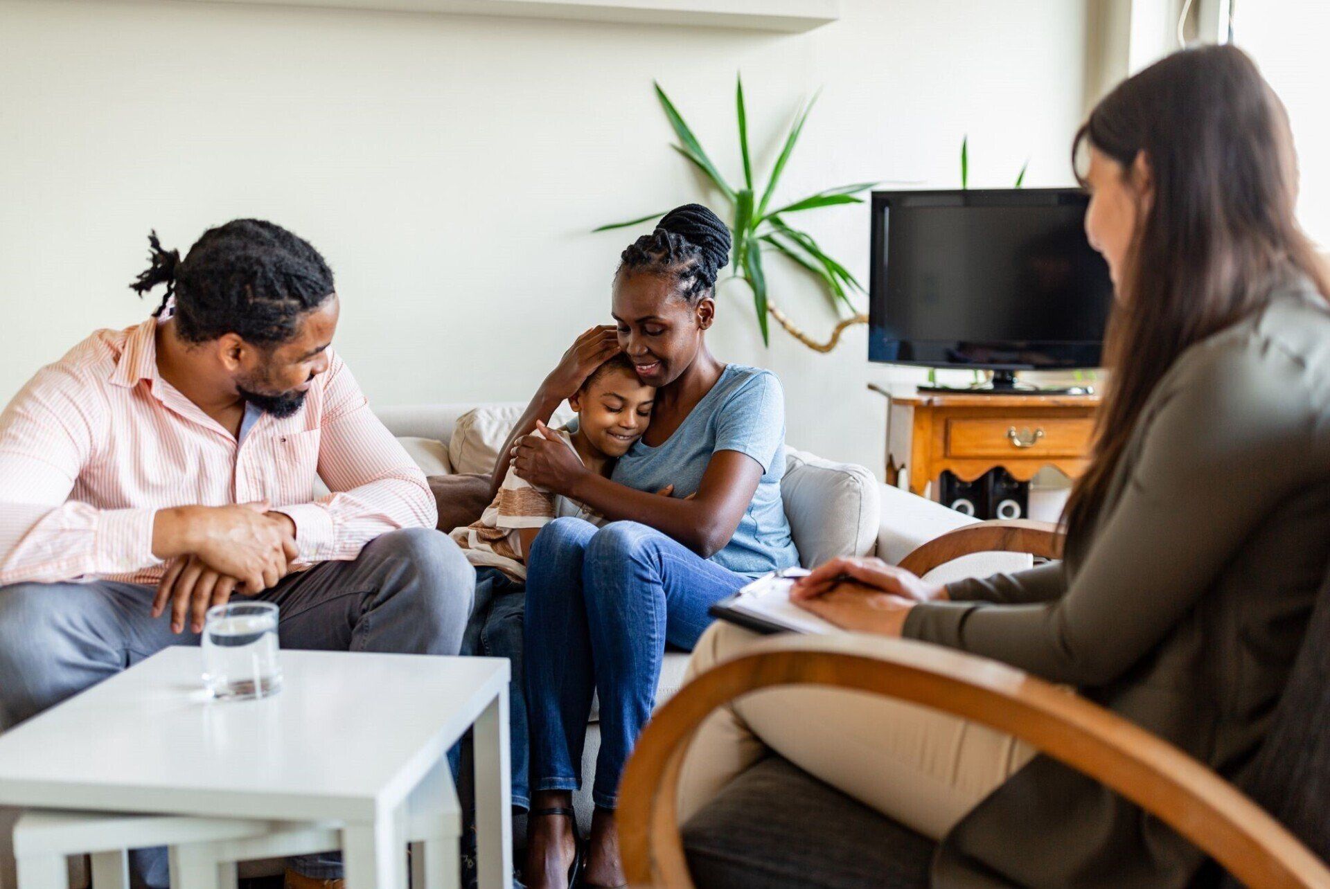 Four people chatting in a bright living room, seated on a couch and chairs around a coffee table.
