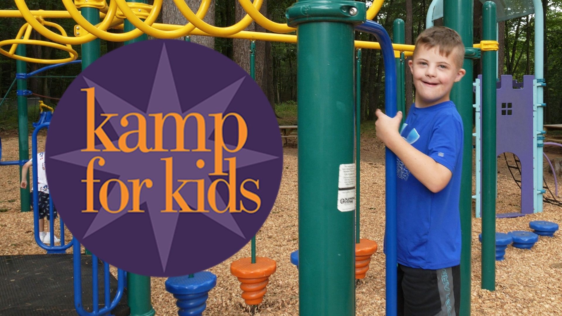 Kamp for Kids sign beside a smiling child on playground equipment