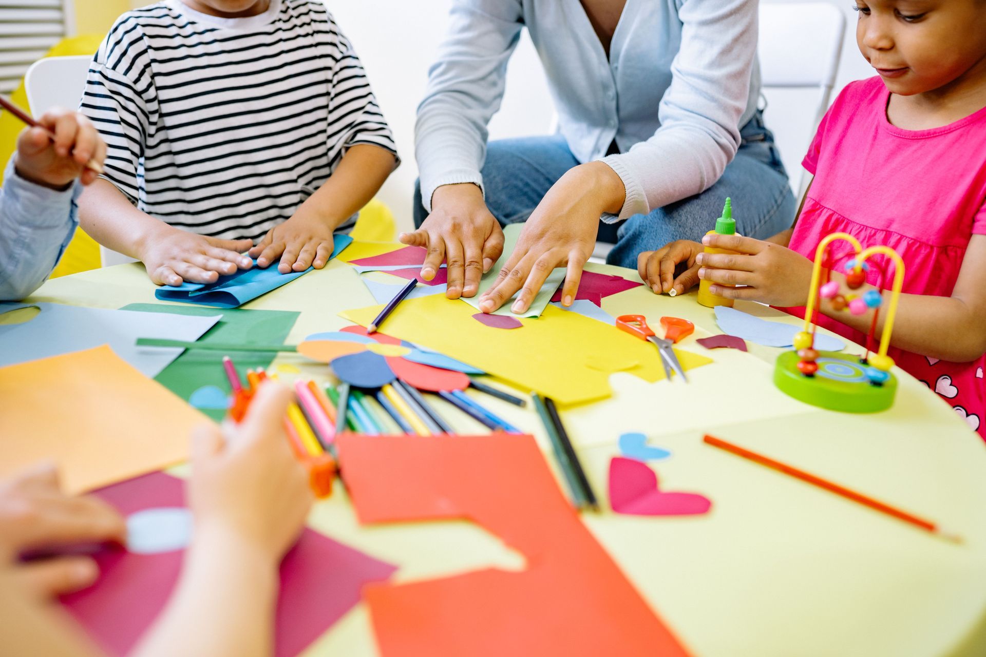 preschool kids and a teacher doing art project with paper