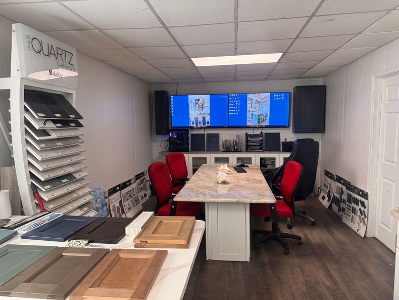 Conference room with long table, red chairs, blue wall screens, and shelves of documents and samples