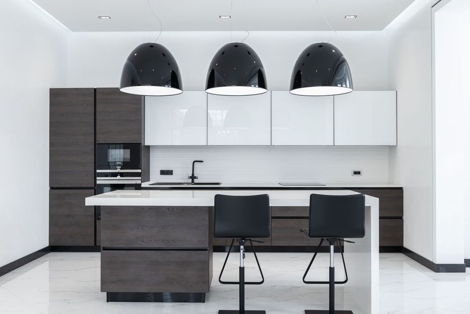 Modern white and dark wood kitchen with island, two stools, and black pendant lights