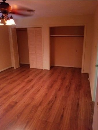 An empty room with hardwood floors and a ceiling fan.