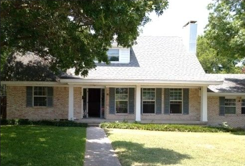 A brick house with white shutters on the windows